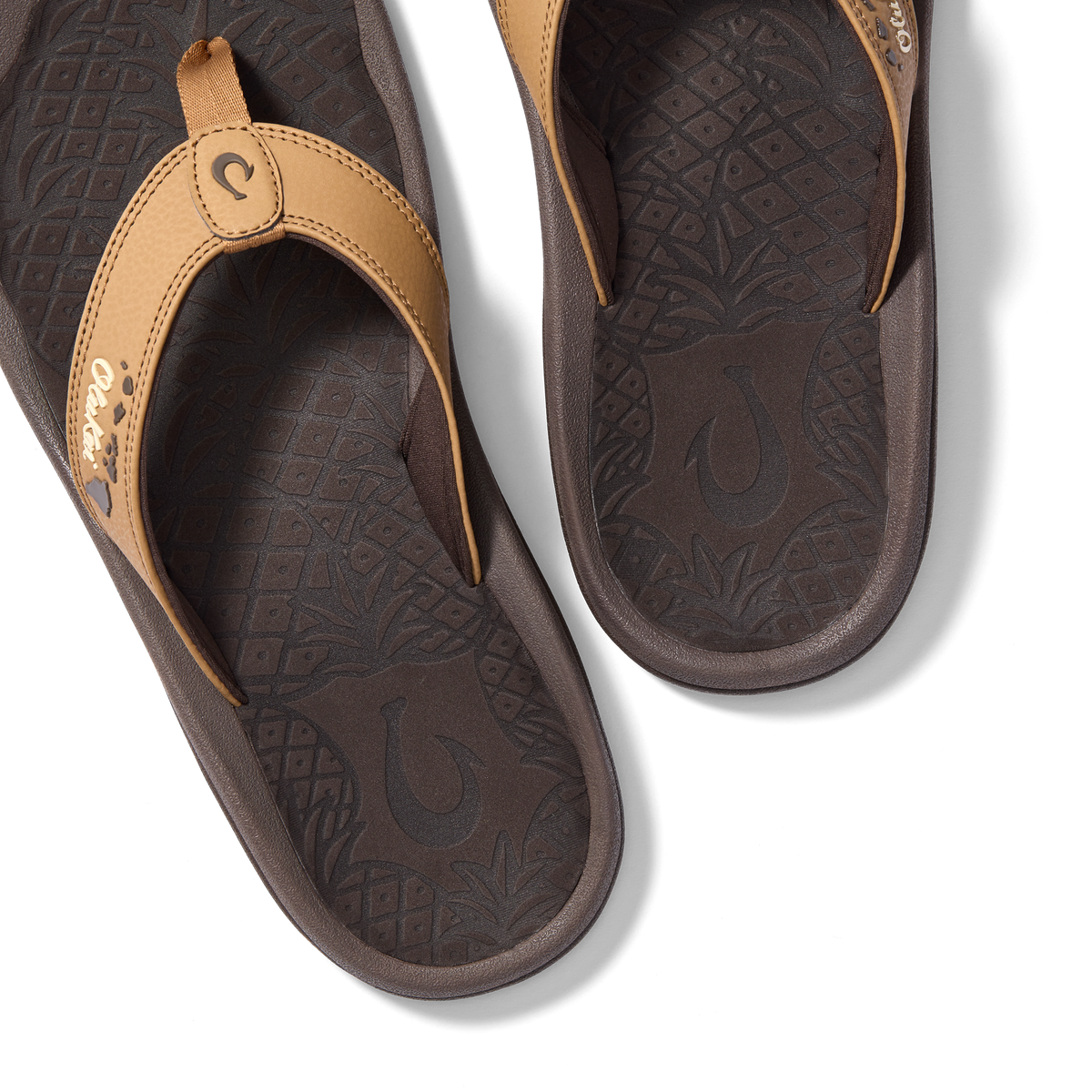 Tan and dark brown flip-flops with patterned footbeds and decorative toe straps, shown from above.