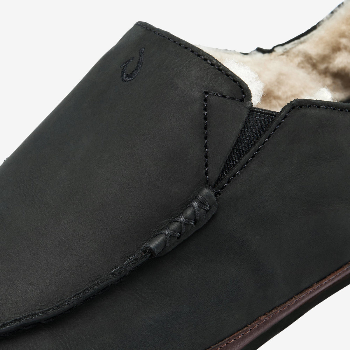 Black leather slipper with fleece lining, showing elastic gusset and stitched detailing on the upper.