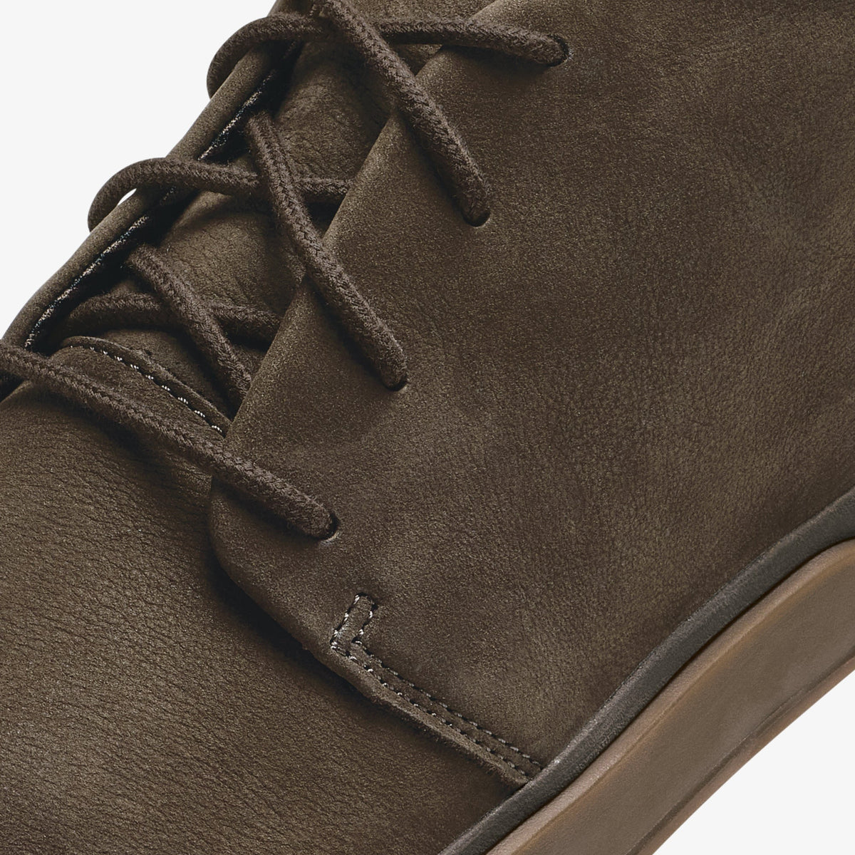 Dark brown suede boot with lace-up closure and tan sole visible.