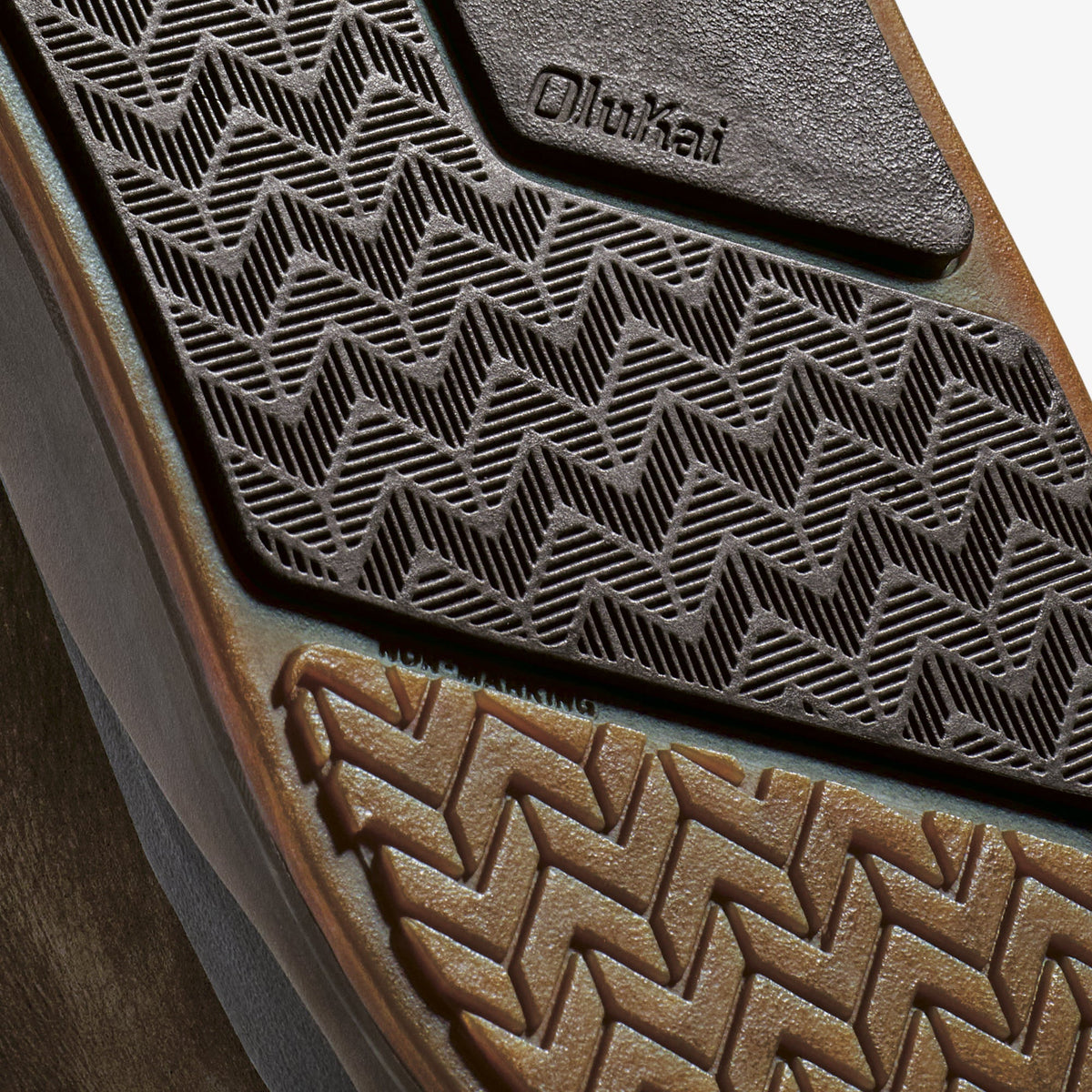 Dark rubber car mat with geometric pattern and Olukai branding on corner flap.