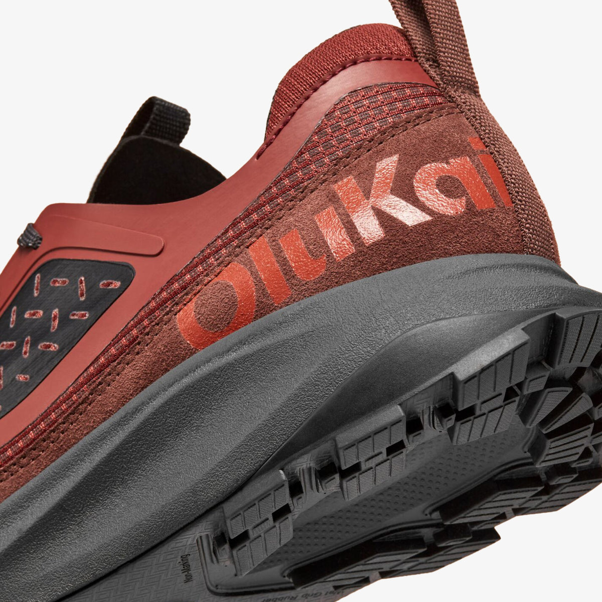 Red and brown athletic shoe with "Quikki" branding, gray rubber sole, and black heel tab, shown from side angle.