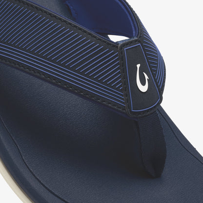 Navy blue flip-flop with horizontal striped upper strap, white hook logo, and cream-colored sole.