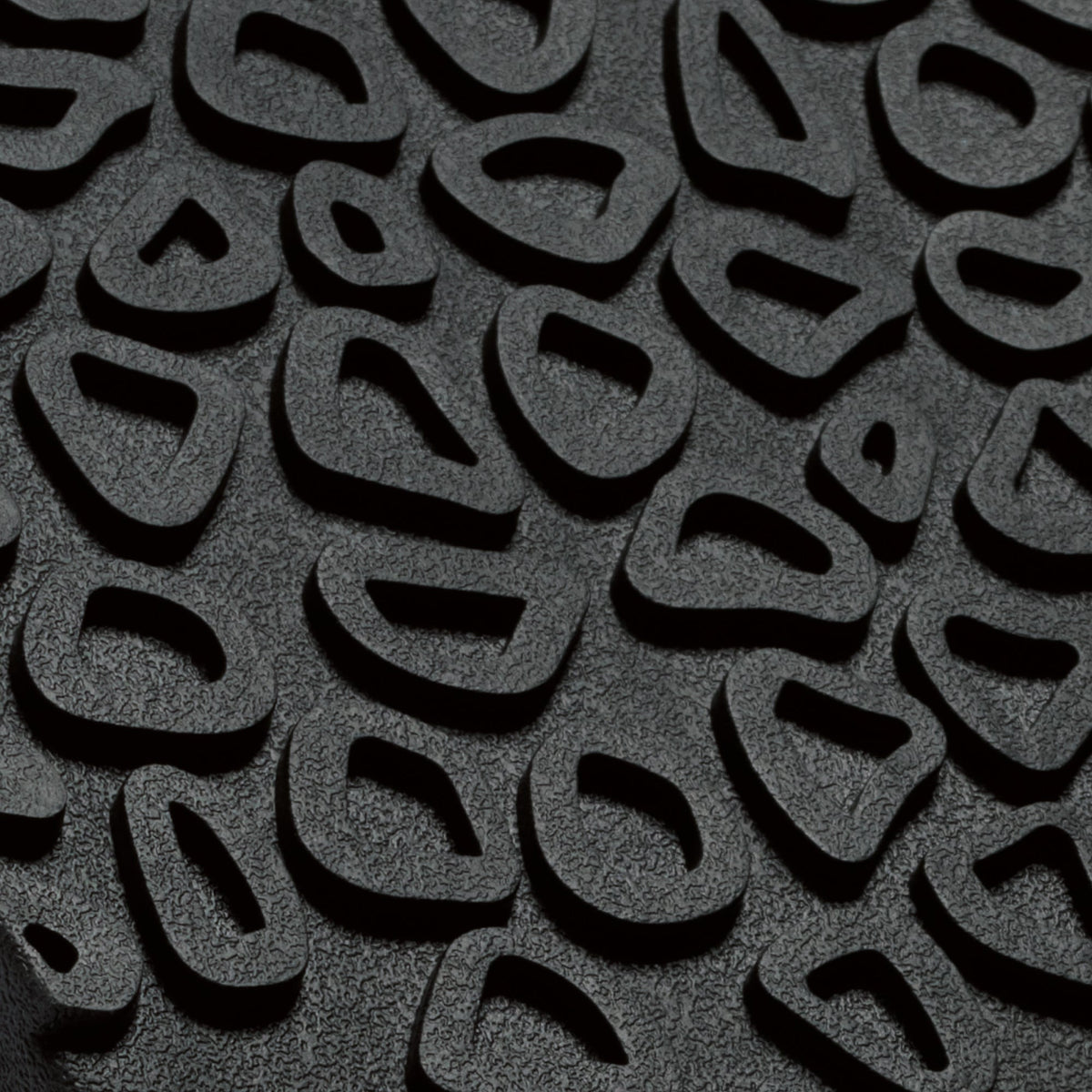 Dark gray textured surface with repeating curved cutout pattern and shadow details.