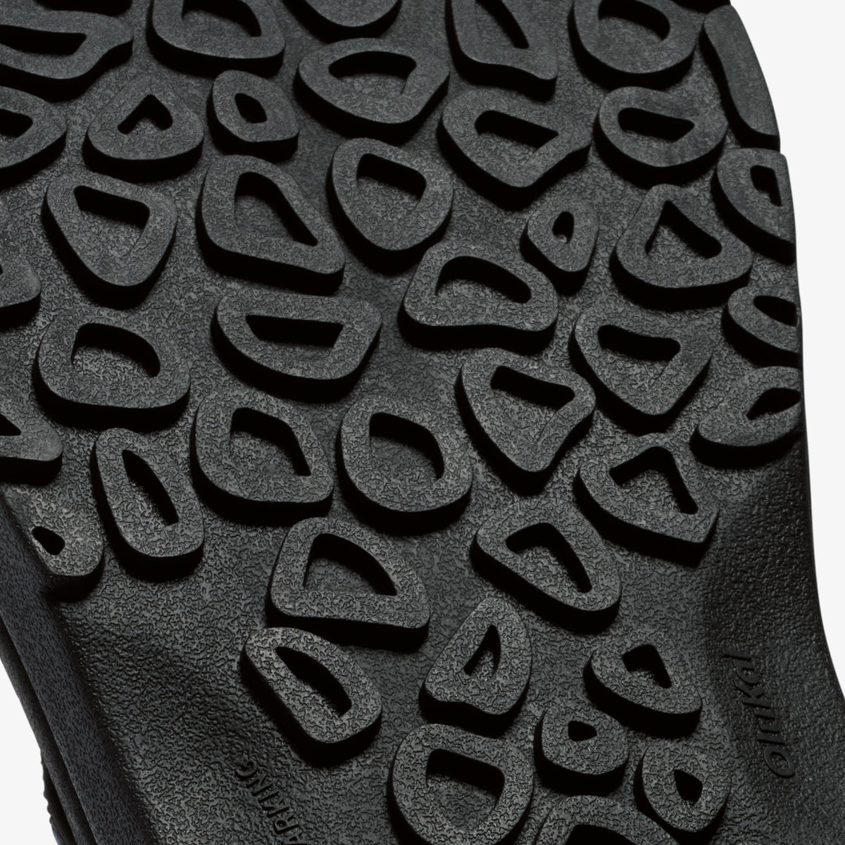 Close-up of textured sole with repeating geometric cutout pattern in gray and black tones.