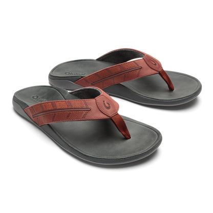 Pair of flip-flops with gray footbeds and rust-colored textured straps with circular buckle details.