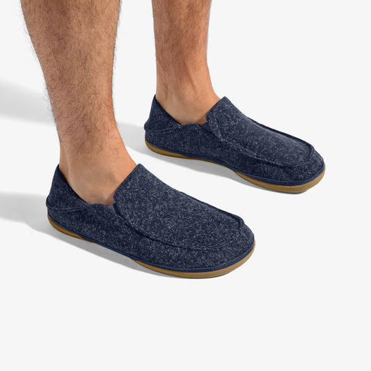 Man wearing dark blue heathered slip-on slippers with tan rubber soles.