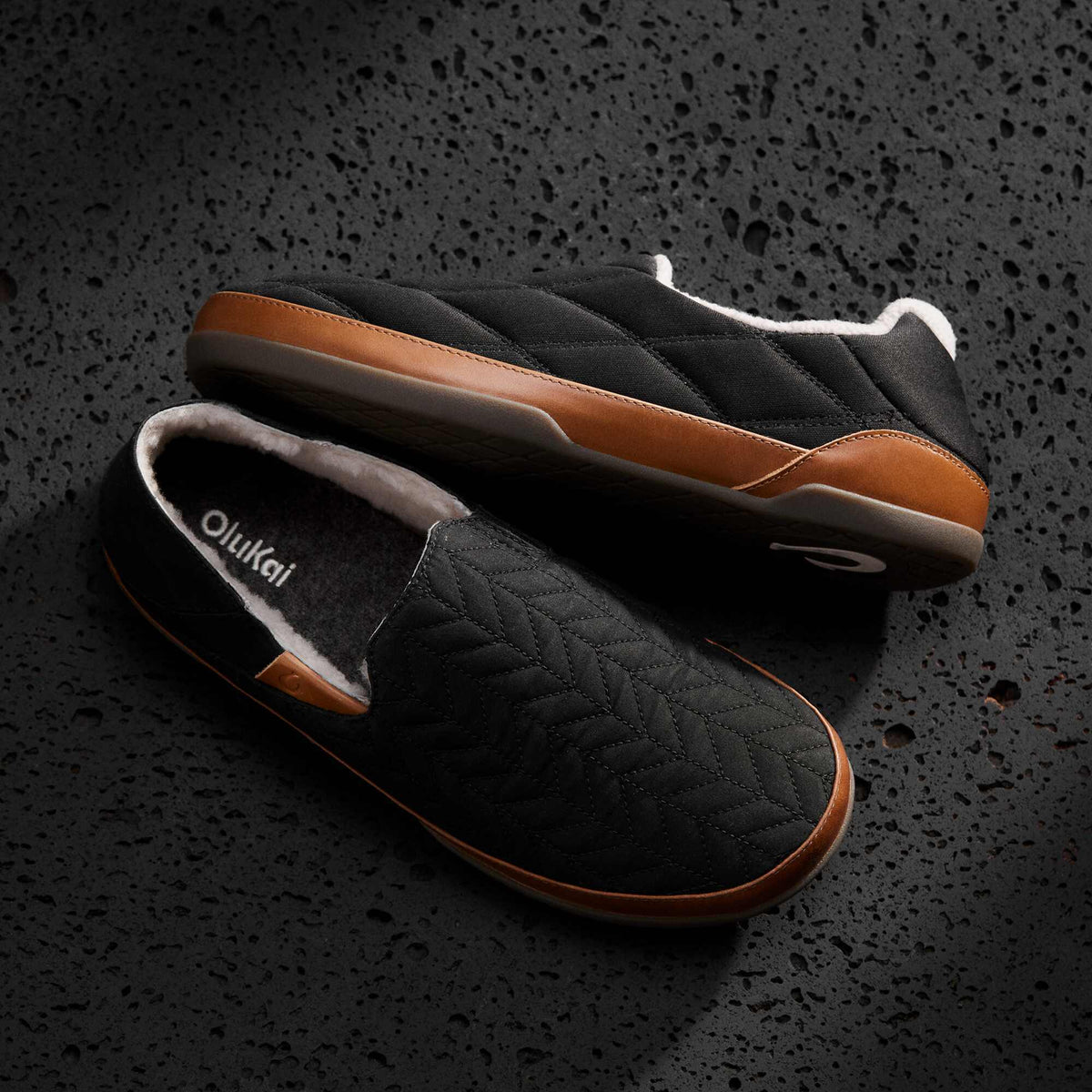 Black quilted slip-on slippers with tan leather sole and fleece lining, shown from top and side angles.