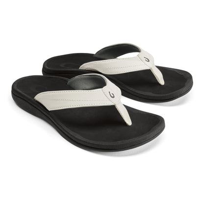 Pair of black flip-flops with bright white thong straps and black padded soles.