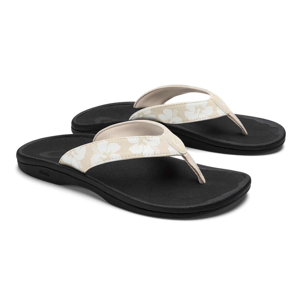 Pair of black flip-flop sandals with cream and beige floral patterned straps and curved footbeds.