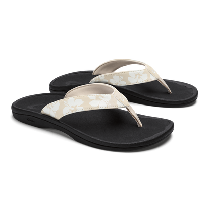 Pair of black flip-flop sandals with cream and beige floral patterned straps and curved footbeds.