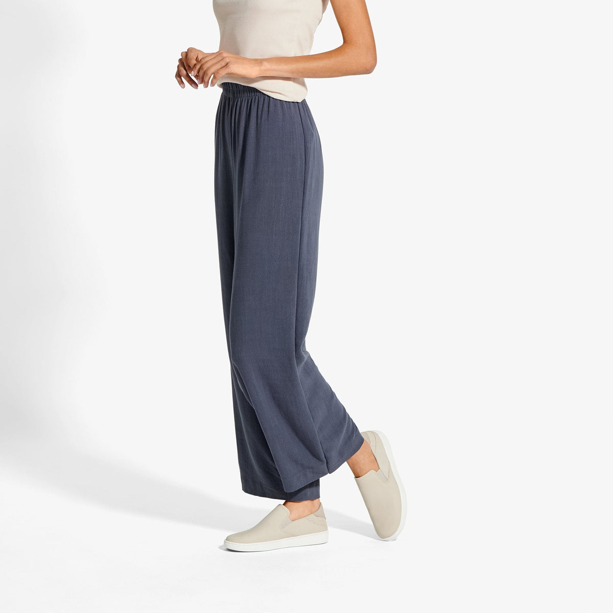 Woman wearing navy wide-leg pants with elastic waistband and cream slip-on leather shoes.