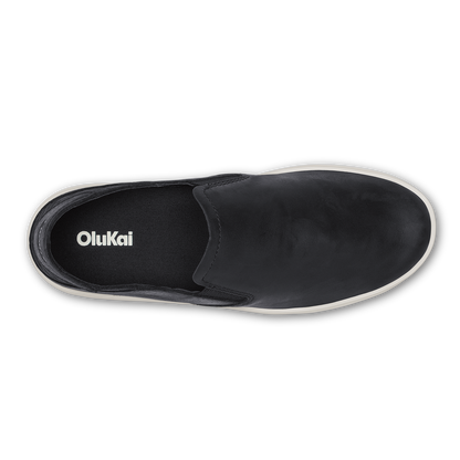 Black leather slip-on shoe with white sole and OluKai branding on insole, viewed from above.