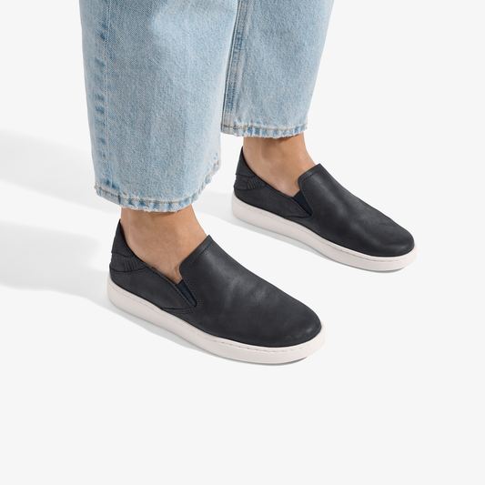 Black leather slip-on shoes with white sole, styled with light blue jeans.