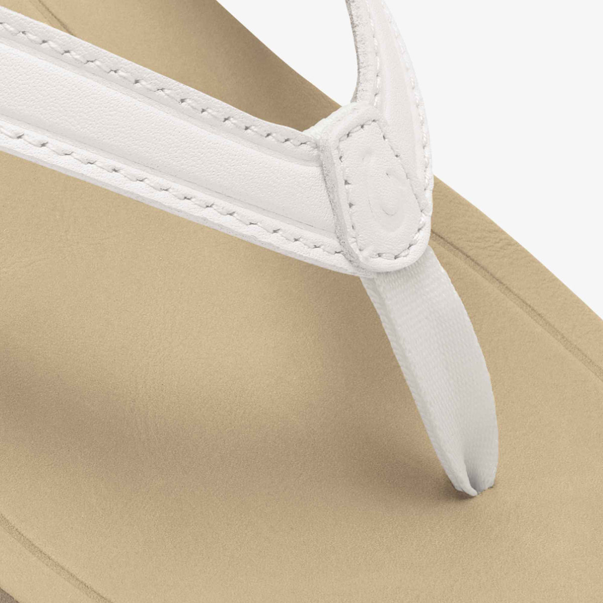Bright white leather strap sandal with warm sand-colored footbed and stitched toe post detail.