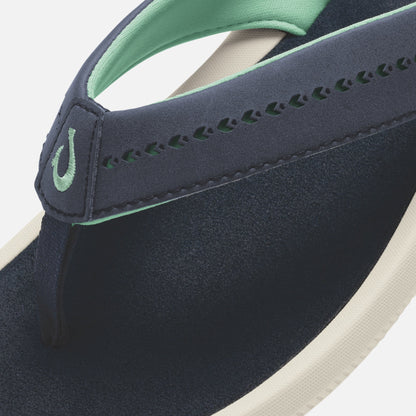 Dark navy flip-flop with mint green strap, cream sole, and decorative stitching detail.