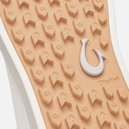 Sole of white sneaker with textured peach-toned tread pattern and white/gray curved logo detail.