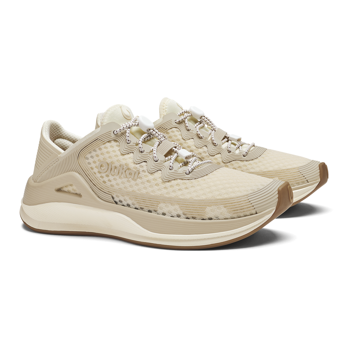 Cream and tan running shoe with textured upper, rhinestone lace detailing, and curved sole design.