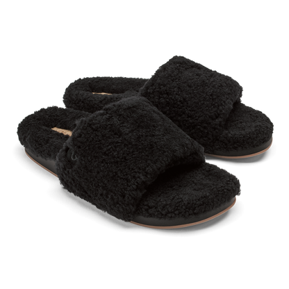 Pair of black fuzzy slippers with tan leather soles and cushioned footbeds.