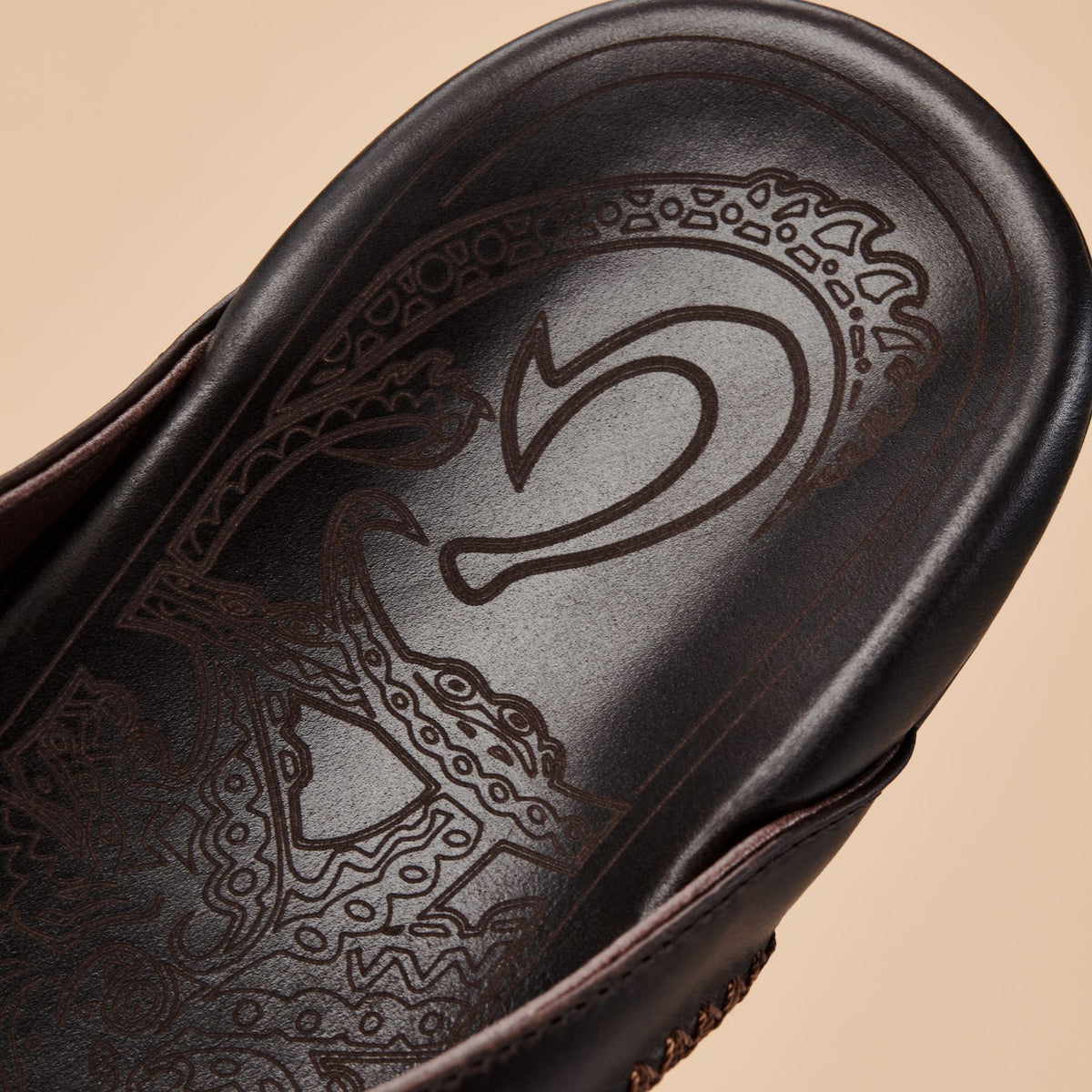 Dark brown leather shoe with embossed number 5 and ornamental geometric patterns on the sole.